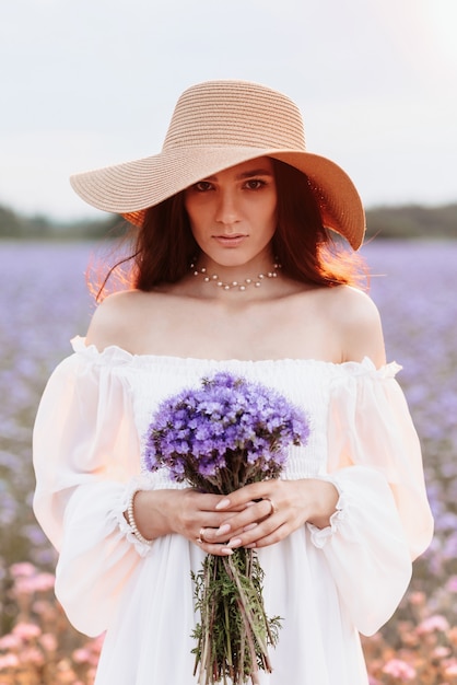 Retrato de uma bela jovem em um vestido branco em um campo florido de provença.