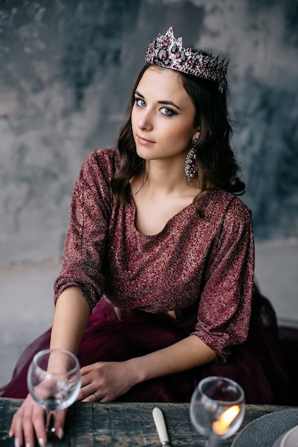 Foto retrato de uma bela jovem em uma imagem da rainha, vestido colorido marsala