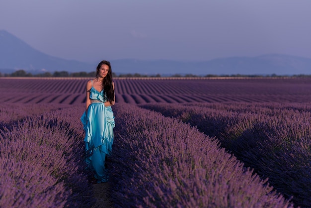 retrato de uma bela jovem em vestido cyand relaxando e se divertindo no vento no campo de flores de lavanda roxa