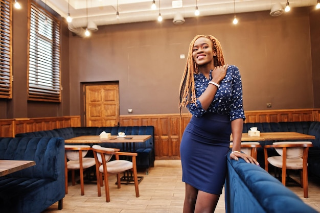 Retrato de uma bela jovem empresária africana com dreadlocks vestindo blusa azul e saia posada no café