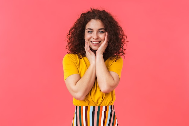 Retrato de uma bela jovem encaracolada feliz fofo posando isolado na parede vermelha.