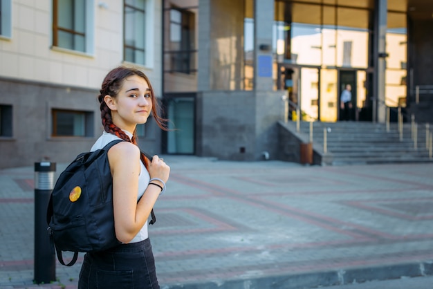 Retrato de uma bela jovem estudante com uma mochila e longas tranças