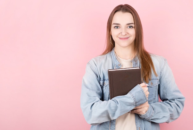 Retrato de uma bela jovem estudante segurando um livro e olhando