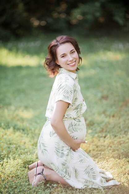 Retrato de uma bela jovem grávida no vestido de eco. Maternidade. Uma família. Verão.