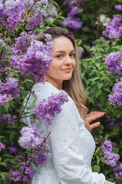 Retrato de uma bela jovem loira de olhos azuis perto da primavera lilás florescente