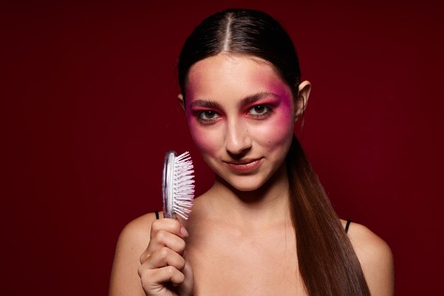 Retrato de uma bela jovem maquiagem emoções cosméticos cuidados com o cabelo fundo rosa inalterado