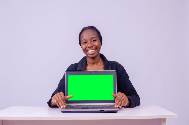 Retrato de uma bela jovem negra mostrando a tela do laptop, ela está sorrindo