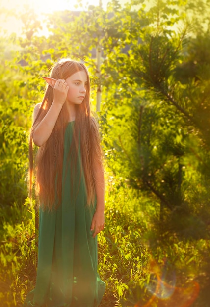 Retrato de uma bela jovem vestida como um elfo na floresta ao pôr do sol