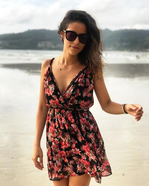 Foto retrato de uma bela jovem vestindo um vestido de sol na praia
