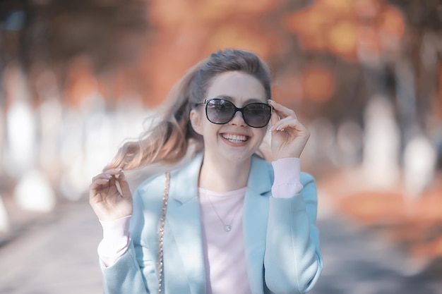 retrato de uma bela modelo feminino europeu usando óculos escuros / menina andando ao ar livre, garota alegre feliz usando óculos