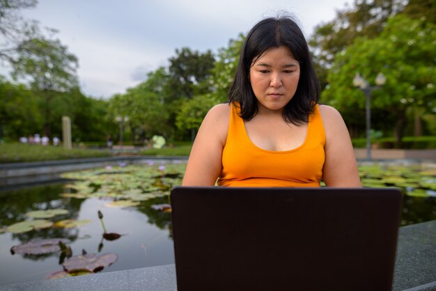 Retrato de uma bela mulher asiática com excesso de peso relaxando no parque na cidade de Bangkok, Tailândia