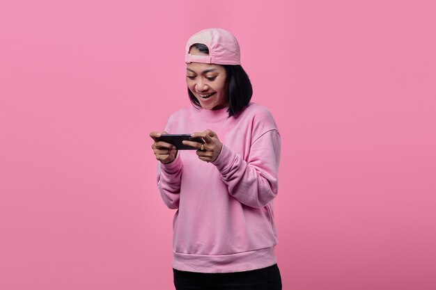 Retrato de uma bela mulher asiática jogando videogame em um smartphone com expressão de felicidade