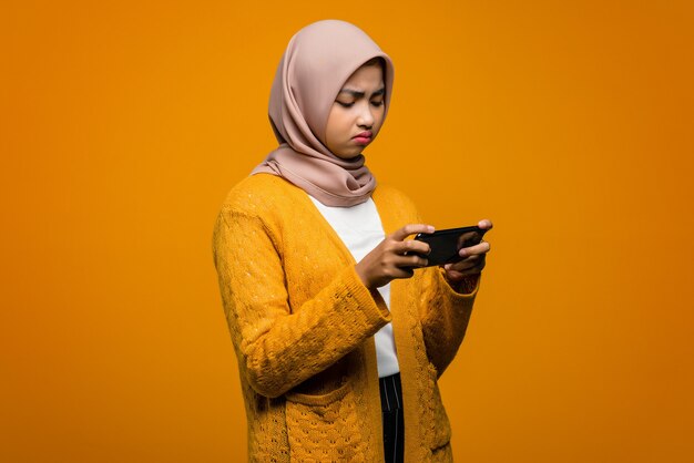 Retrato de uma bela mulher asiática jogando videogame em um smartphone com uma expressão triste