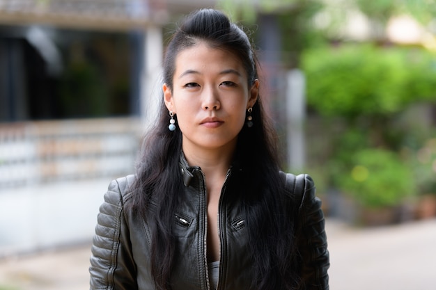 Retrato de uma bela mulher asiática rebelde vestindo jaqueta de couro na rua ao ar livre
