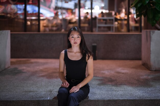 Retrato de uma bela mulher asiática sentada ao ar livre à noite