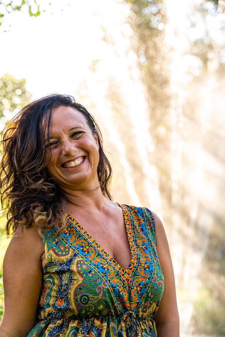 Foto retrato de uma bela mulher de meia-idade em frente a uma fonte em um parque ao pôr do sol