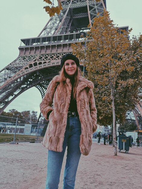 Foto retrato de uma bela mulher de pé contra a torre eiffel