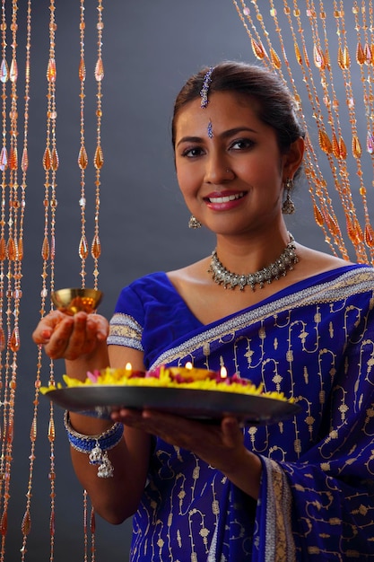 Foto retrato de uma bela mulher indiana em sari segurando ofertas religiosas durante o diwali