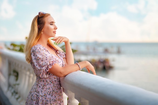 Retrato de uma bela mulher loira posando na balaustrada e olhando para o oceano Espaço de cópia O conceito de liberdade de férias de verão e psicologia