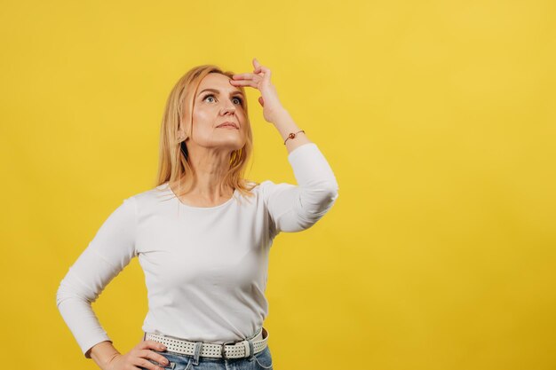 Retrato de uma bela mulher madura pensando isolado em fundo amarelo