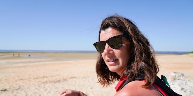 Retrato de uma bela mulher morena de 40 anos de idade em uma excursão de verão na praia de areia