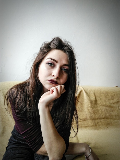 Retrato de uma bela mulher sentada no sofá em casa
