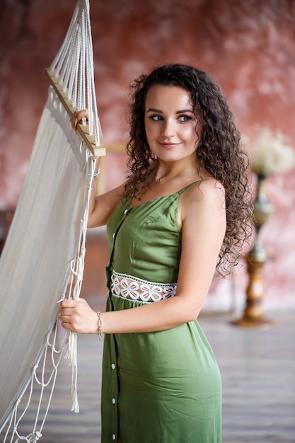 Retrato de uma bela mulher sorridente de aparência europeia em um vestido com penteado de cachos. Moda e beleza