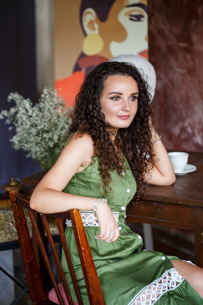 Retrato de uma bela mulher sorridente de aparência europeia em um vestido com penteado de cachos. moda e beleza