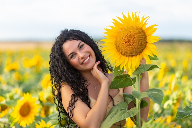 Retrato de uma bela mulher sorridente de cabelos escuros com um buquê de girassóis