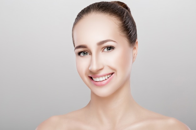 Retrato de uma bela mulher sorridente em fundo cinza closeup. menina com pele limpa