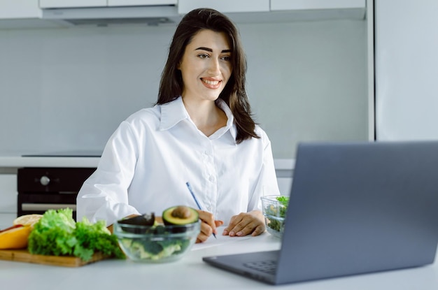 Retrato de uma bela nutricionista sorridente olhando para a câmera e mostrando vegetais saudáveis na consultaTrabalhar em casaConceito de comida saudável