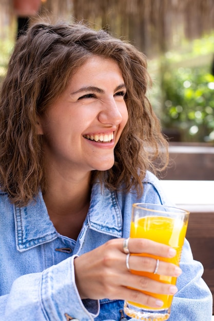 Foto retrato de uma beleza morena jovem e saudável com copo de suco de laranja e frutas