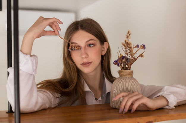 Retrato de uma blogueira feminina com flores secas dentro de casa