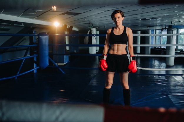 Retrato de uma boxeadora com luvas vermelhas na academia durante o treinamento