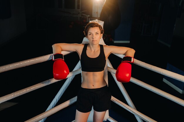 Retrato de uma boxeadora com luvas vermelhas na academia durante o treinamento