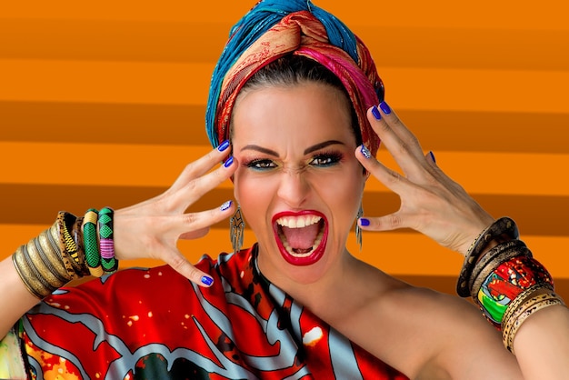Retrato de uma cantora jovem e atraente gritando em estilo africano em parede colorida
