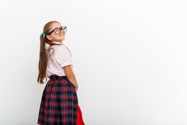 Retrato de uma colegial de uniforme em pé no fundo branco