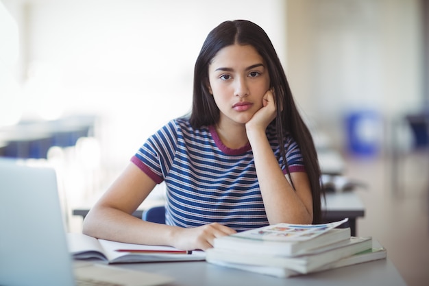 Retrato de uma colegial triste sentada na sala de aula