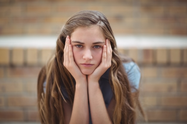 Retrato de uma colegial triste sentada sozinha no campus