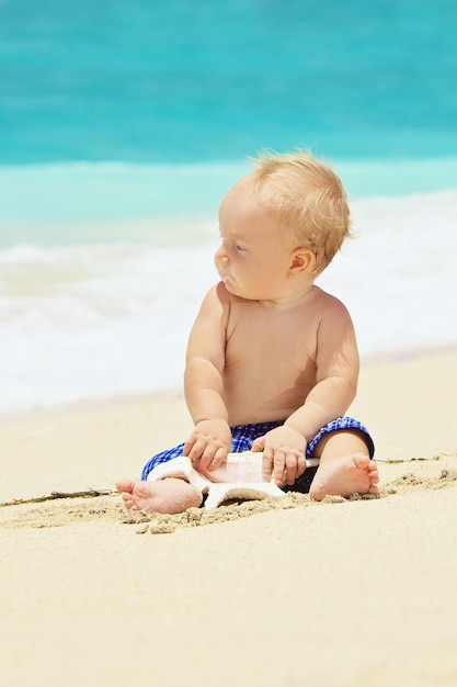 Foto retrato de uma criança com concha do mar em uma praia tropical