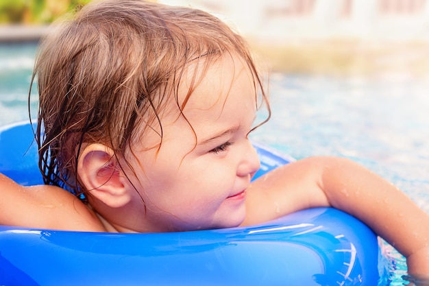 Retrato de uma criança feliz em um flutuador inflável na piscina