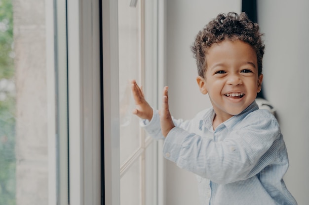 Retrato de uma criança negra alegre com um sorriso adorável se divertindo em casa