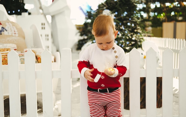 Foto retrato de uma criança no fundo de uma árvore de natal menino brinca com um presente conceito c