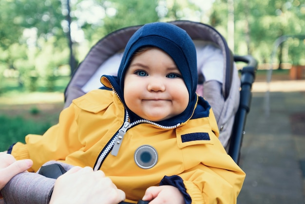 Retrato de uma criança pequena, bebê com macacão amarelo sentado no carrinho no parque