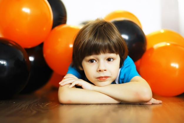 Retrato de uma criança pequena deitada no chão em uma sala decorada com balões. Conceito de infância feliz.