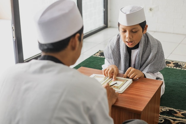 Retrato de uma criança religiosa muçulmana aprendendo a ler o Alcorão em roupas de estilo árabe na mesquita