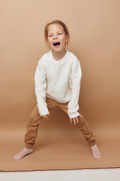 Retrato de uma criança sorridente feliz em suéter branco posando gestos de mão estilo de vida inalterado