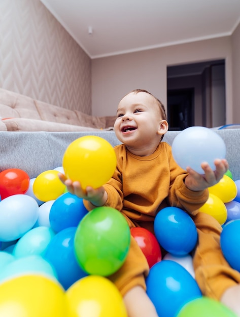 Retrato de uma criança sorridente sentada entre bolas coloridas Criança brincando na piscina Brinquedos de atividades para crianças