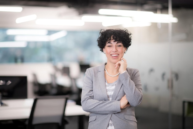 Retrato de uma desenvolvedora de software bem-sucedida com um penteado encaracolado em um escritório de startups moderno