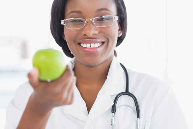Retrato de uma doutora sorridente segurando uma maçã